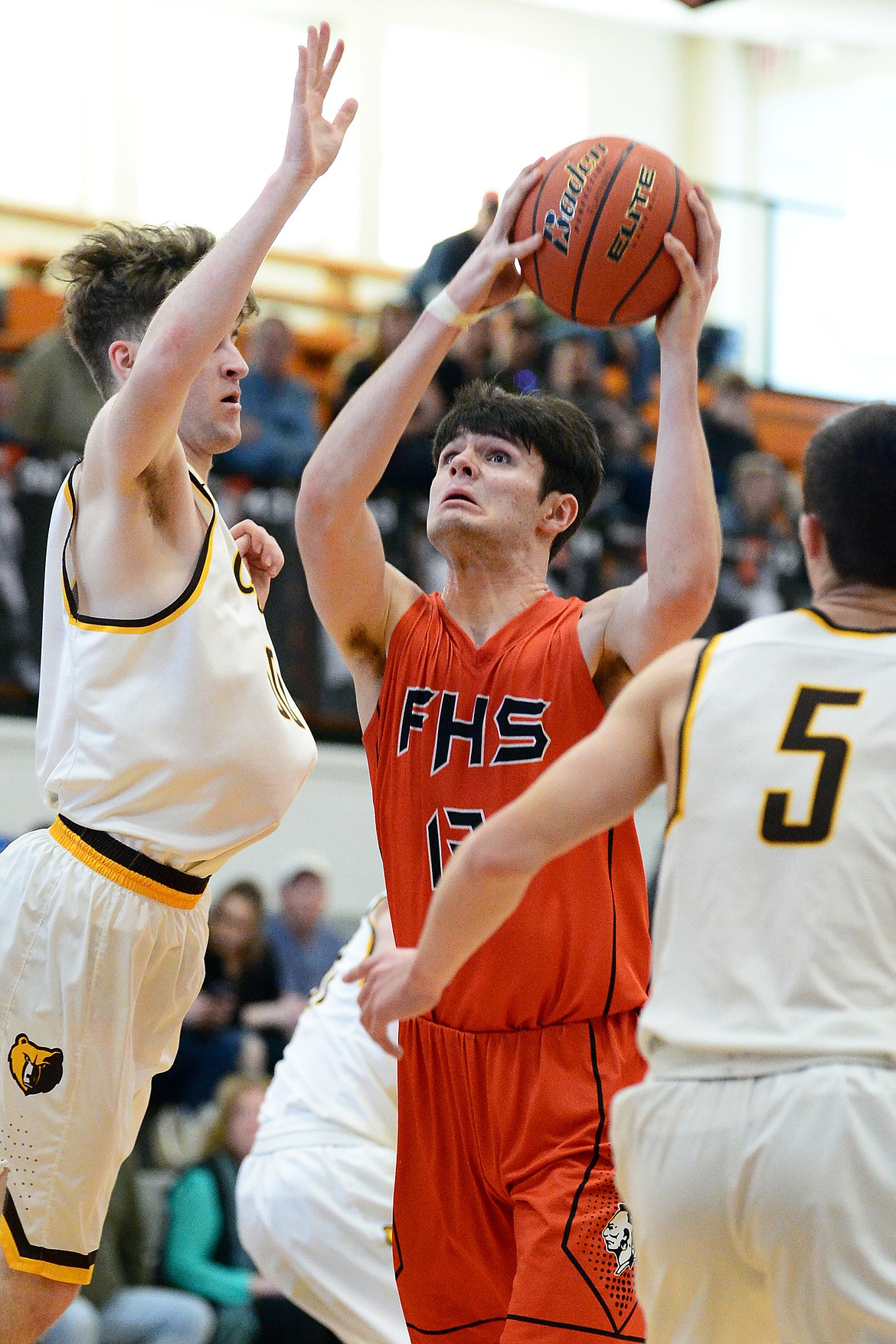 Flathead's Gabe Adams (13) works his way to the hoop past Helena Capital's Kaleb Metzger (50) and Trevor Swanson (5) at Flathead High School on Saturday. (Casey Kreider/Daily Inter Lake)