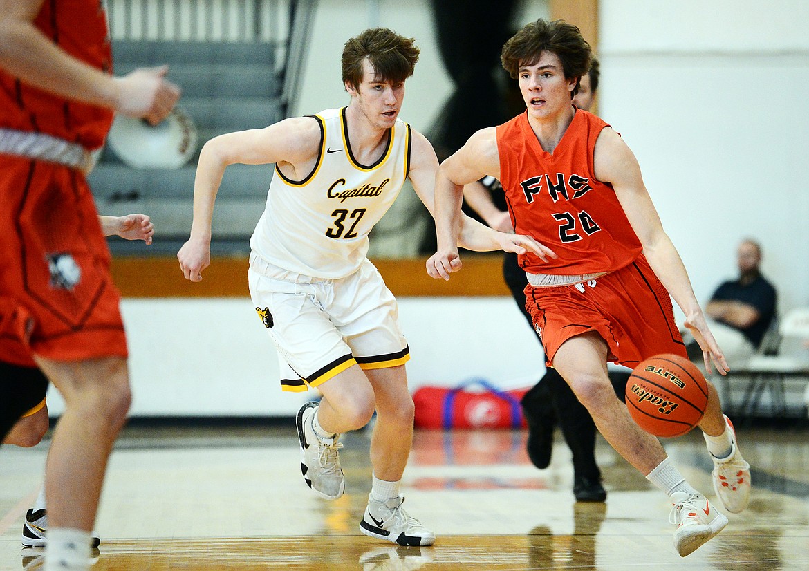 Flathead's Cooper Smith (20) brings the ball upcourt against Helena Capital's Shane Haller (32) at Flathead High School on Saturday. (Casey Kreider/Daily Inter Lake)