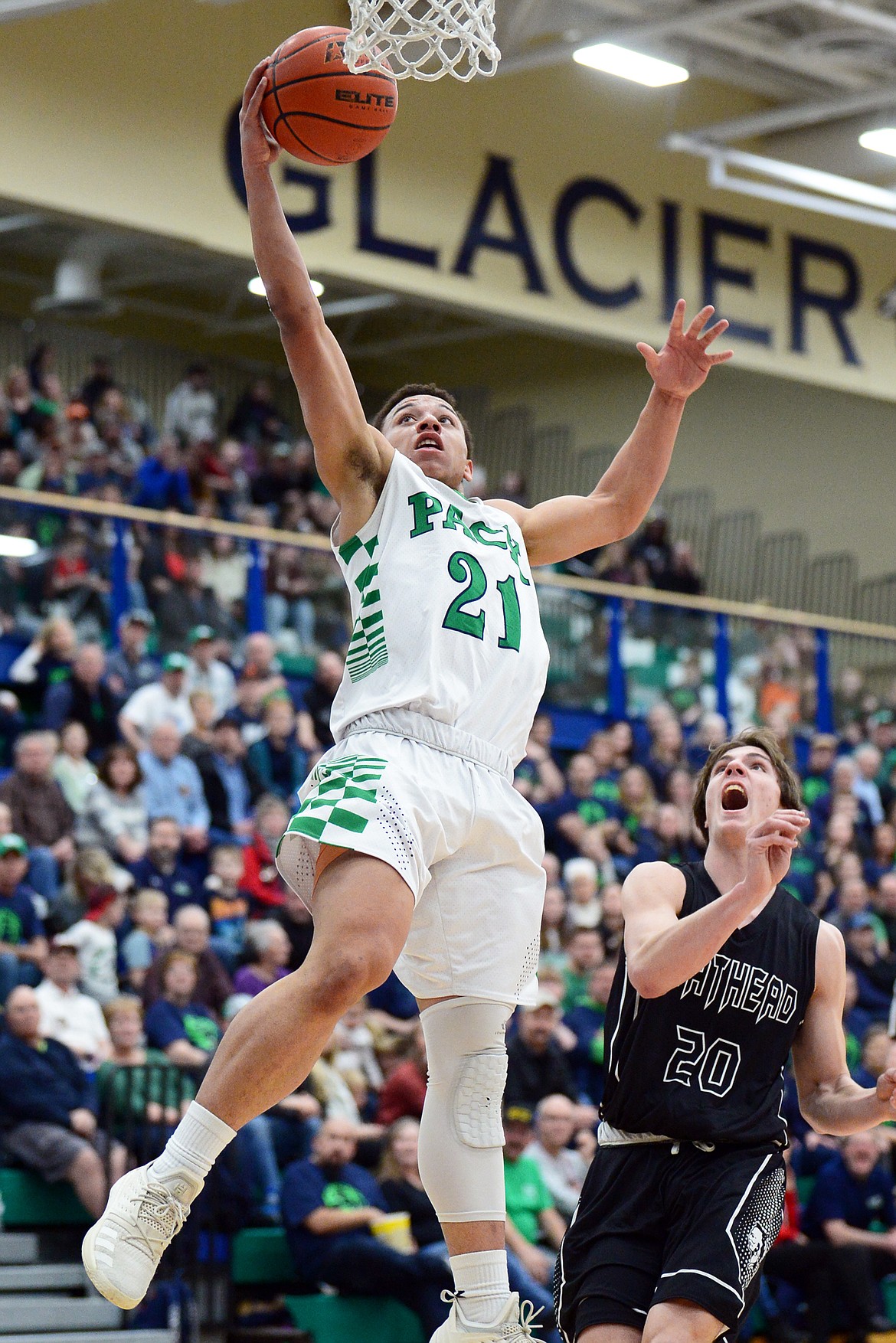 Glacier's Anthony Heath (21) drives to the hoop with Flathead's Cooper Smith (20) trailing during a crosstown matchup at Glacier High School on Friday. (Casey Kreider/Daily Inter Lake)