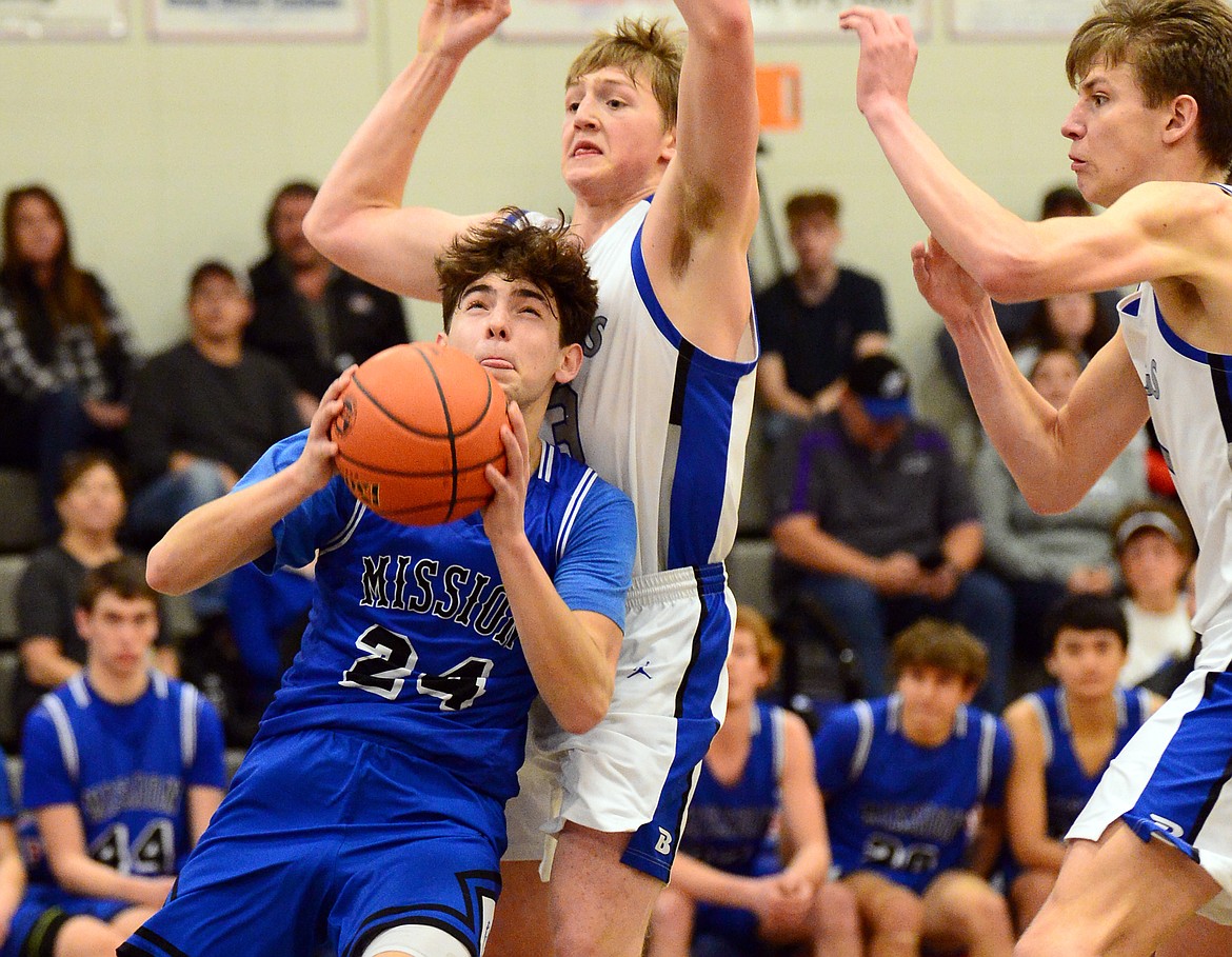 Mission's Jedi Christy (24) drives to the basket against Bigfork's Isaac Bjorge (23) and Colt Thorness (1) at Bigfork High School on Thursday. (Casey Kreider/Daily Inter Lake)