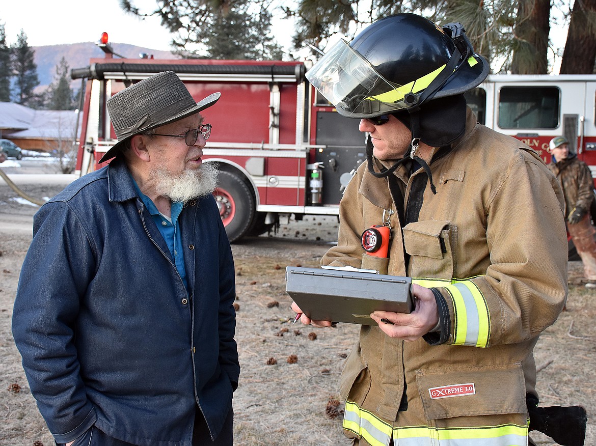 Homeowner Ora Miller, left, recounts how he discovered the fire to Dan Knapp of the Libby Volunteer Fire Department. (Duncan Adams/The Western News)