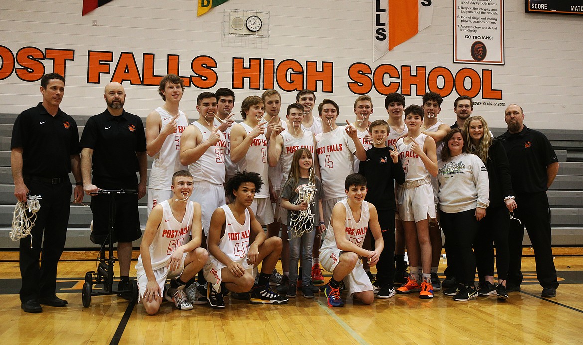 With head coach Mike McLean (second from left) perched on a knee scooter, the Post Falls basketball team poses with the 5A Region 1 championship trophy last week after defeating Lewiston. 

LOREN BENOIT/Press