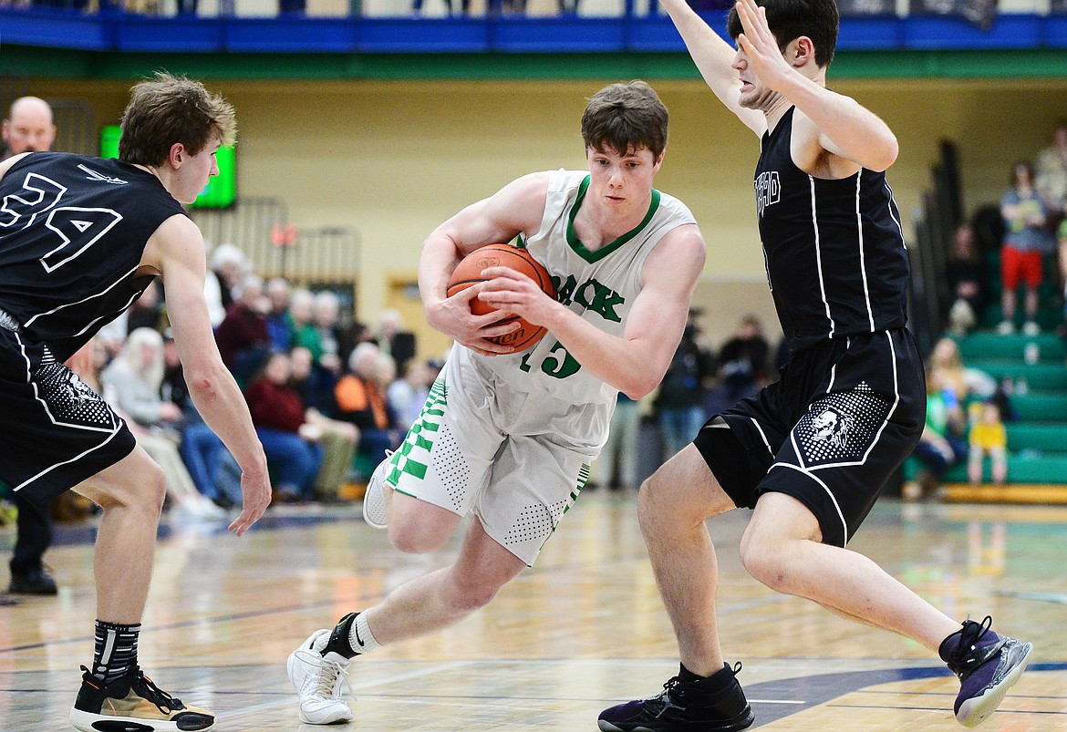 Glacier's Drew Engellant (15) drives the lane between Flathead's Joston Cripe (34) and Gabe Adams (13) during a crosstown matchup at Glacier High School on Friday. (Casey Kreider/Daily Inter Lake)