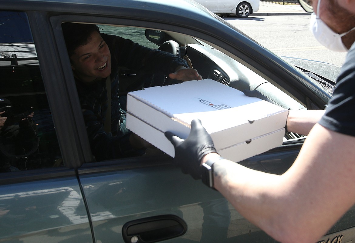 Caid Wood grabs his curbside order from Fire Pizza CDA employee Jeromy Hebert Wednesday. (LOREN BENOIT/Press)