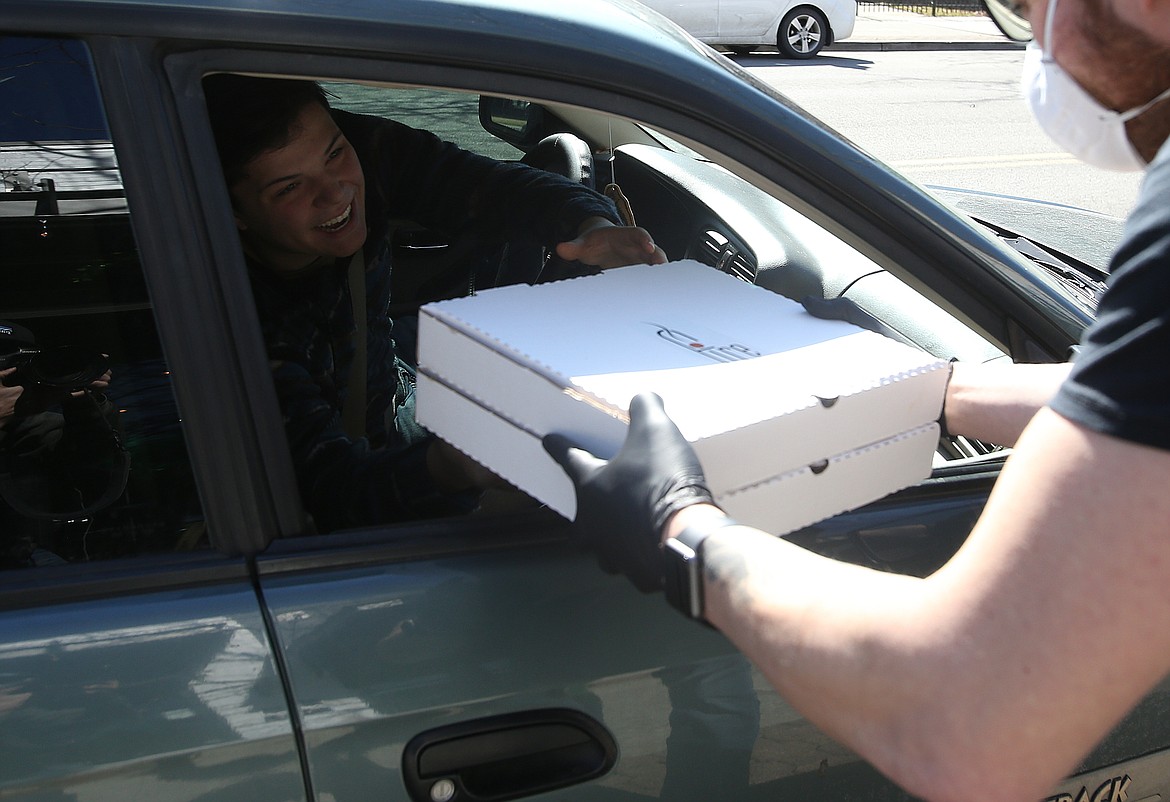 Caid Wood grabs his curbside order from Fire and Artisan employee Jeromy Hebert Wednesday. (LOREN BENOIT/Press)