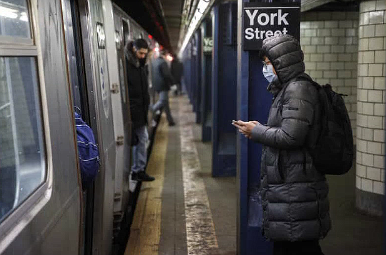 A subway customer wearing a face mask waits to board a car in the Brooklyn borough of New York, Monday, March 16, 2020. New York leaders took a series of unprecedented steps Sunday to slow the spread of the coronavirus, including canceling schools and extinguishing most nightlife in New York City. According to the World Health Organization, most people recover in about two to six weeks, depending on the severity of the illness. (AP Photo/John Minchillo)