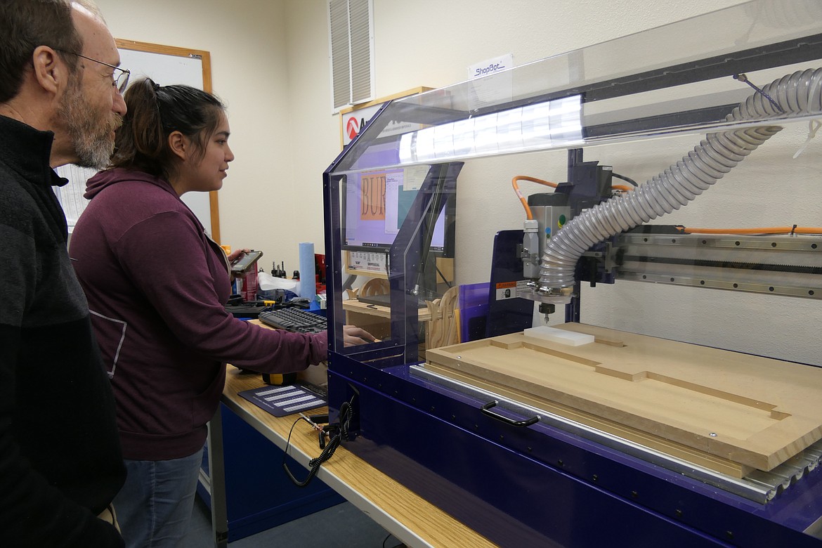 Ellie Costilla readies a name plate design for the CNC router, with assistance from instructor Thomas Trickel.