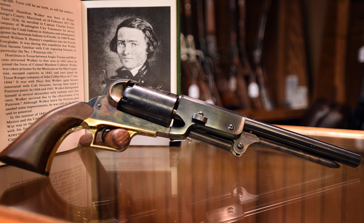 A replica of the 1847 Walker Colt revolver rests in front of a photo of designer Captain Samuel Hamilton Walker.