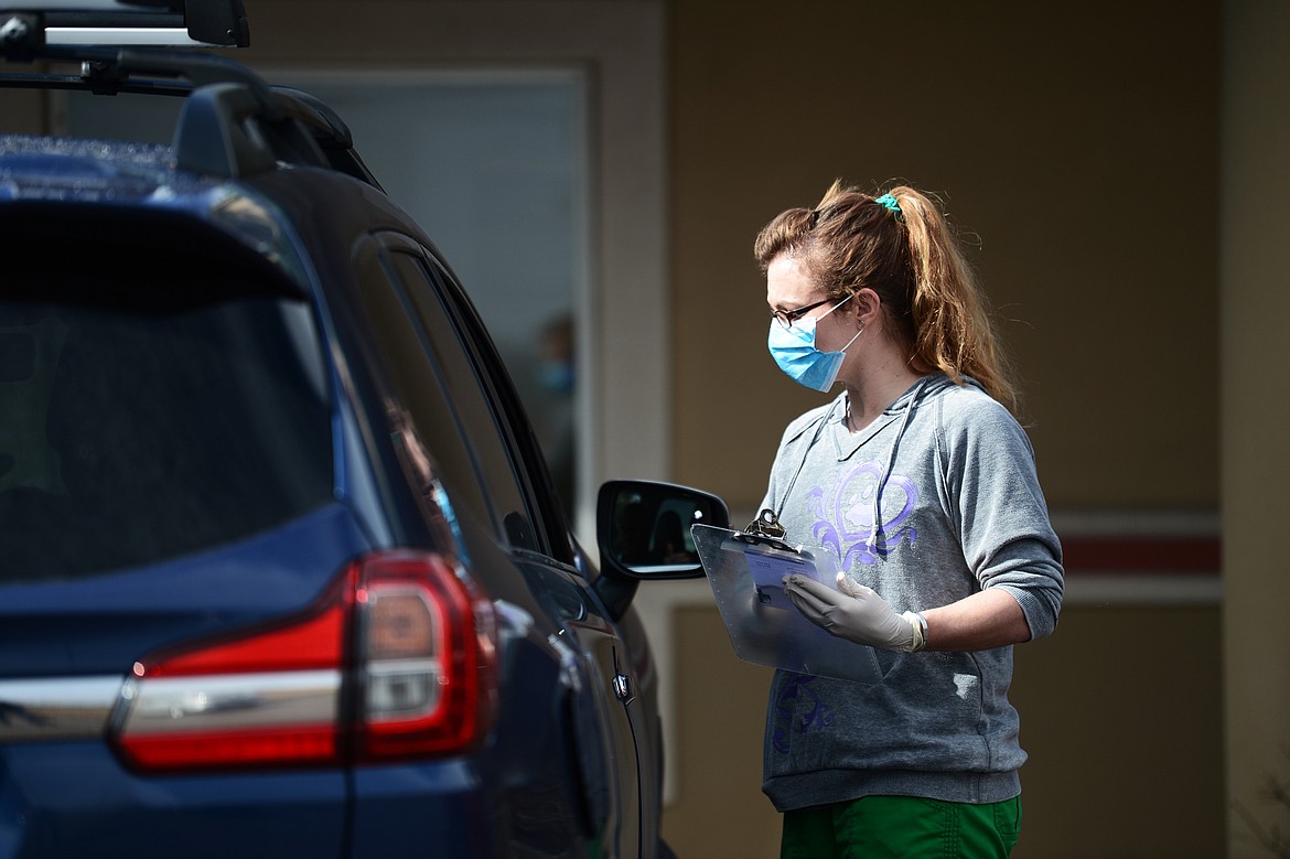 Pam Joyce, with Central Valley Animal Hospital, speaks to a client in the parking lot outside the clinic on Tuesday, March 24. (Casey Kreider/Daily Inter Lake)