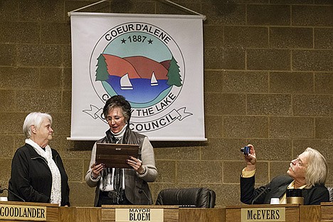 &lt;p&gt;Outgoing mayor Sandi Bloem reads from a plaque while presenting it to Deanna Goodlander, outgoing city council member, just moments before their terms ended. Woody McEvers, returning council member, later voted council president, takes photographs of the moment.&lt;/p&gt;