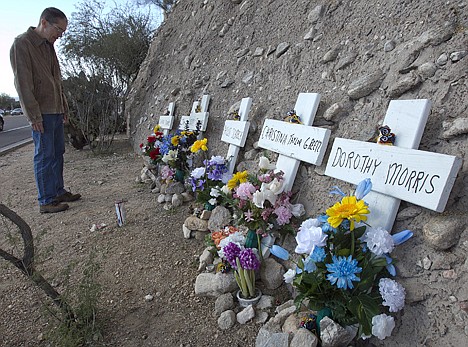 &lt;p&gt;Matt McLear, 48, of Tucson, Ariz., looks at a memorial of flowers Sunday and crosses across the street from the Safeway where one year ago a shooting at an event for Rep. Gabrielle Giffords left six dead and 13 injured, including Giffords, in Tucson.&lt;/p&gt;