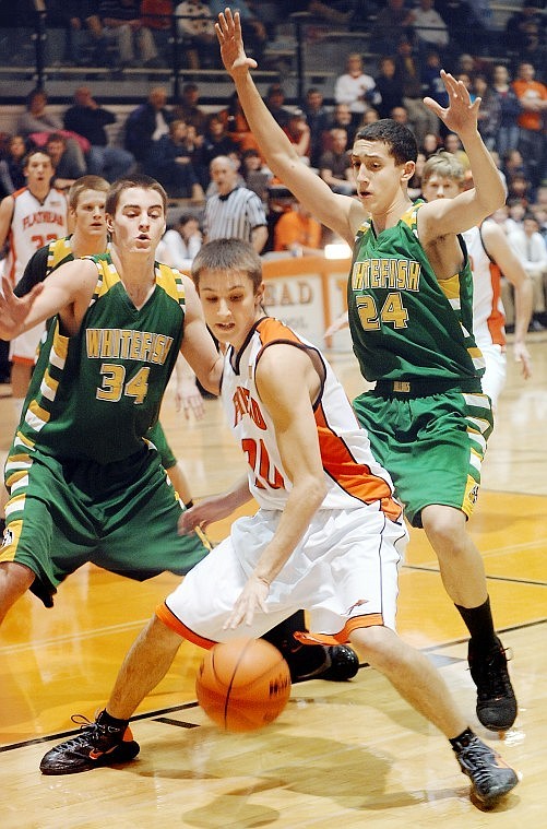 Flathead senior Tanner Salois (20) is pressured by Whitefish senior Connor Silliker (34) and sophomore Gage Vasquez (24) during Friday nights nonconference basketball game at Flathead.