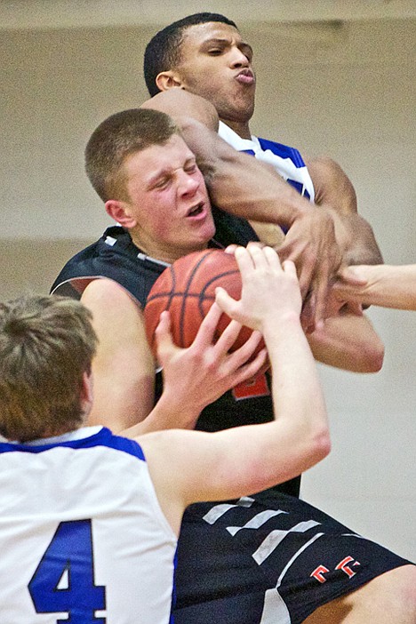 <p>Post Falls High's Michael Hillman fights to hold onto the ball as Deon Watson from Coeur d'Alene High reaches over his should to get at the ball during the first half.</p>