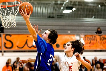 <p>Coeur d'Alene's Brody Lundblad soars past Post Falls' Jacob Pfennigs for a lay-up on Tuesday at Post Falls High School.</p>