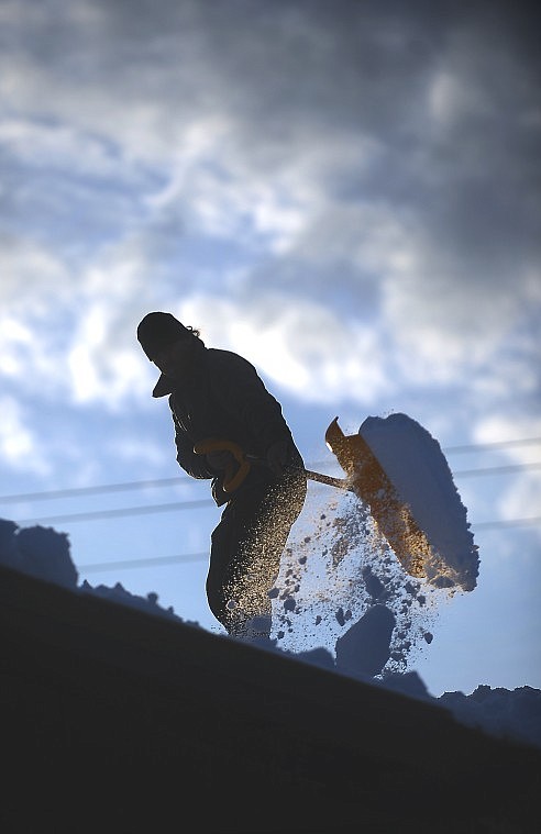 Duane Peterson of Whitefish shovels snow from his roof on Monday. Peterson said he was anticipating rain and did not want to have too much weight on the roof.