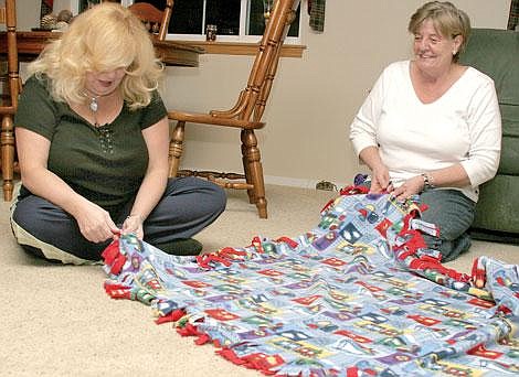 Photos by Sarah Leavenworth&lt;br&gt;Mystic Sisters Debbie Griggs (left) and Shirley Nettleton create fleece blankets for needy community members at group member Paula Petri's home Wednesday evening.