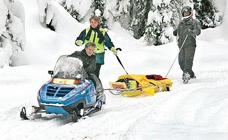 Photo by Mark McDaniel&lt;br&gt;After approximately a two-mile ride on a new rescue sled called a stokes, the rescued woman is eased down a steep hill to an awaiting ambulance by Shirley Garr of the Knightriders Snowmobile Club, accompanied by ambulance crew member Anita Parkin (middle), and Mark Timberman of West End Volunteer Fire and Rescue. Over 20 members of different rescue organizations and other bystanders helped with the rescue.