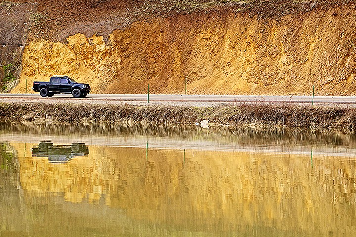 &lt;p&gt;JEROME A. POLLOS/Press A motorist drives past a colorful, weathered hillside Thursday reflected in the surface of Fernan Lake.&lt;/p&gt;