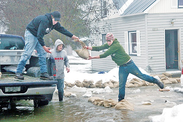 Logan Neubauer hands his brother, Levi Neubauer, a sandbag on West Bush Street just off of Nevada Avenue.