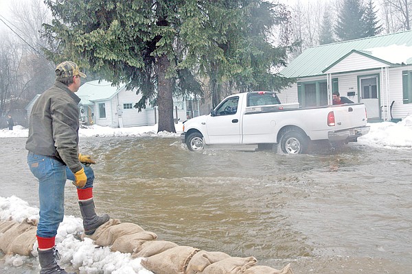 Roger Johnston watches as Frank Burkett helps a driver move his pickup out of the flood&#146;s path on Nevada Avenue at about 9:50 a.m. on Monday. After a few tries, the tires gained traction but had to back up with the current of the water.