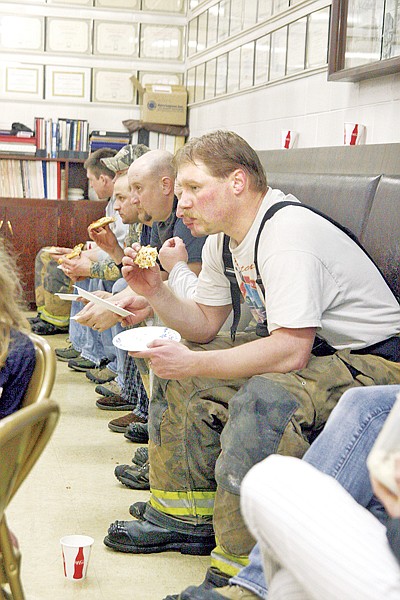 Jason Place, front, and other Libby volunteer firefighters take a pizza break at the fire hall at noon Monday after the flooding began to subside.