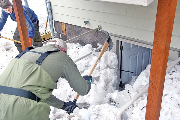 Jay Maloney and Cree Maloney, left, dig through ice and snow that buried the basement entrance to Randy Wiza&#146;s house on Nevada Avenue. When the ice jam broke up, it threw chunks into Wiza&#146;s yard and filled his basement with water.