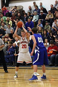 Plains senior Andrew Baker looks for a way to pass around the long arms of Challis Wilson during Friday's 40-59 loss against the Bluehawks.