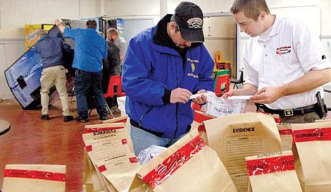 Kalispell Police Department Flathead High School resource officer Carl Brisendine, right and another officer with the Major Crime Unit organize evidence collected from an extensive act of vandalism in the cafeteria at Flathead High late Monday night and early Tuesday morning. On the left, a group of men lift one of the vending machines that was toppled and pryed open. The vandalism suspects are thought to be current or former students. Graffiti was sprayed on the cafeteria walls, some of it directed at a Flathead adminstrator. Karen Nichols/Daily Inter Lake