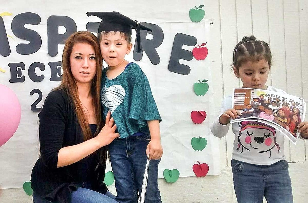 Alejandra Naranjo takes a picture with her graduating daughter Eternity at a recent graduation at the Inspire Early Childhood Education Program. The other daughter, Serenity, waits patiently.