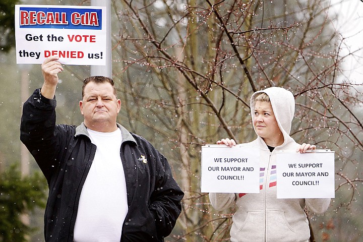 Jennifer Drake glances over at Michael Sheneman as they stand next to each other at a Recall CdA rally as the two display opposite opinions of movement to recall the Coeur d'Alene mayor and half the city council.