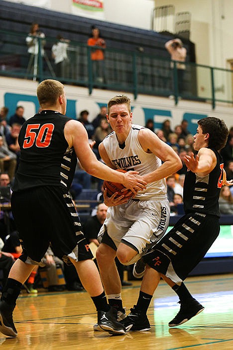 <p>Lake Citys Collin Hunter attempts to break through Post Falls Jake Blakney, left, and Blake McLean during the first half of the Timberwolves game against the Trojans on Tuesday night.</p>