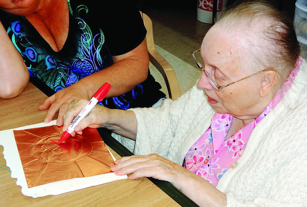 &lt;p&gt;Bev Hamann decorates an embossed foil Aztec sun with the help of an aide. (Sue Cox/Stumptown Art Studio)&lt;/p&gt;