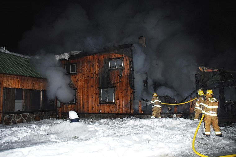 Members of the St. Regis and West End Fire Departments work to put out a blaze in Cabin City last Wednesday evening.