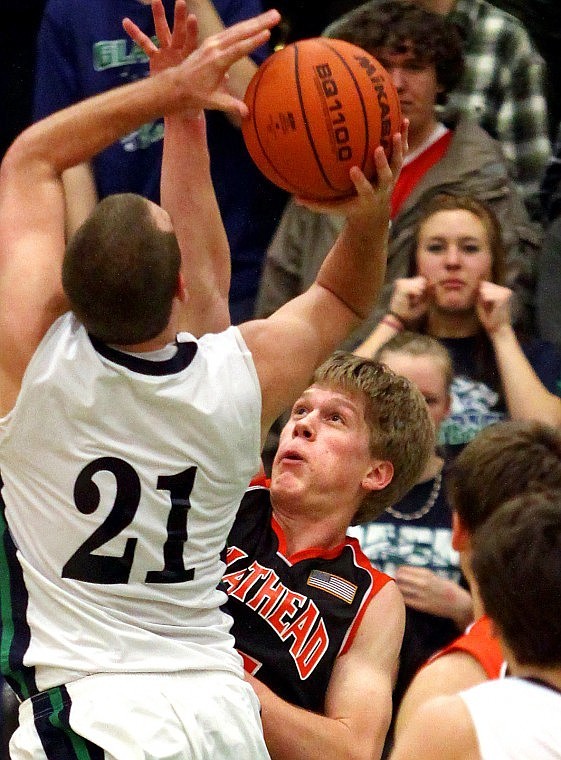 Flathead's Karl Ingram stretches his arm up to defend against Glacier's Shay Smithwick-Hann's shot at the start of the overtime period.