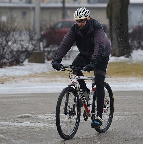 <p>Steve Drecoll of Mundelein doesn't let a mix of snow and rain stop him from riding his bike as he rides through the downtown area on Jan. 3.</p>