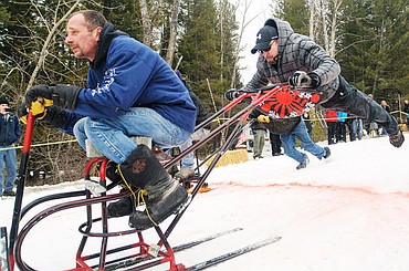 <p>Lenny Hart, right, gives his uncle Buddy Hart a flying push during the World Championship Barstool Races in 2013 at Cabin Fever Days in Martin City. The 2014 edition of Cabin Fever Days is Friday through Sunday.</p>