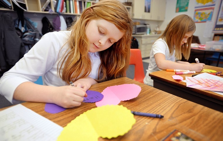 Sara Pearce, 10, of Kalispell, left, and Gillian Broughton, 9, of Columbia Falls decorate Valentine Blessing cards on Monday at Whitefish Christian Academy. On Friday students from the school will take cards and gifts to Whitefish area retirement communities.