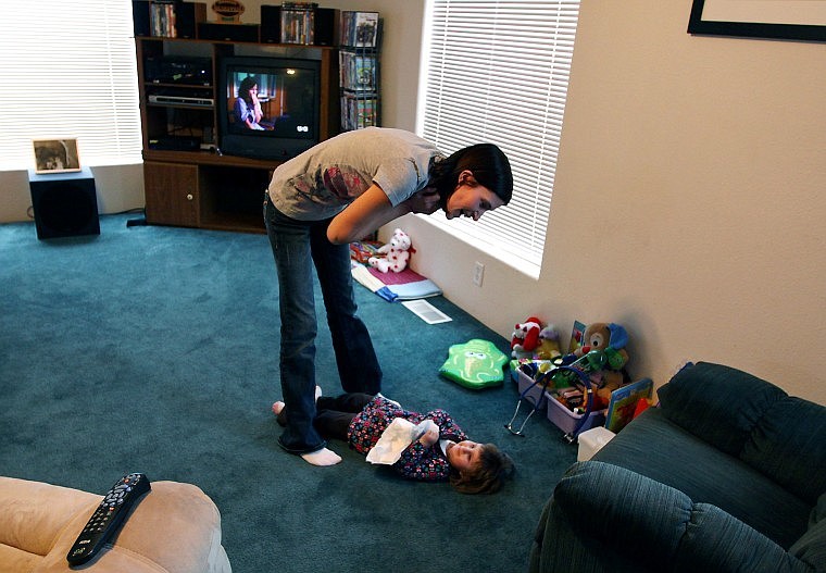 Jennifer Belston looks down at her 3-year-old daughter Tasha as she lies on the floor at their home on Tuesday afternoon. Tasha has Cockayne syndrome, a rare genetic disorder that causes premature aging.
