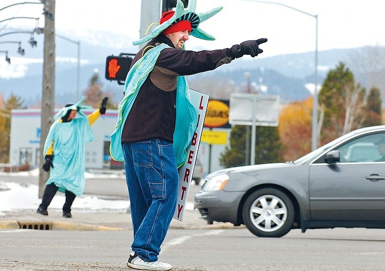 Scott Purdy points toward a passing driver while co-worker Anthony Tressel waves from the corner of U.S. 2 West and Meridian Road on Tuesday afternoon. The two were advertising for Liberty Tax Service.