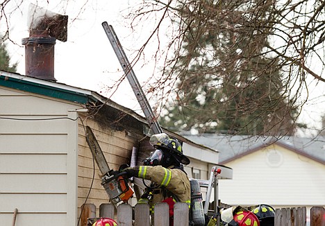 &lt;p&gt;A Coeur d'Alene Fire Department firefighter uses a chainsaw to remove the siding while fighting a fire in the rear of the home on Pennsylvania Avenue.&lt;/p&gt;