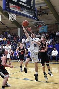 Thompson Falls junior Sky Hall drives past Andrew Baker and in front of Wade Bache of Plains.