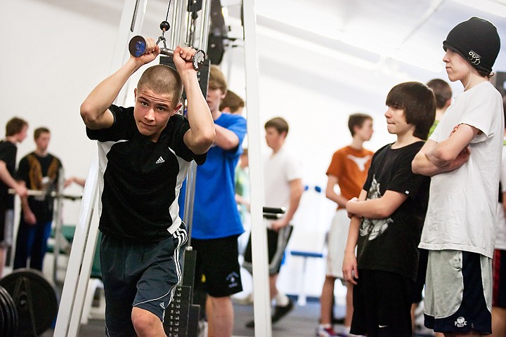 Aaron Noice, a freshman at Coeur d'Alene High School, works his triceps wile doing a pull choice exercise Wednesday during a weigh lifting class.  Shawn Amos, advanced weights instructor at CHS, is hoping to upgrade weight lifting equipment to provide a more efficient space for students.