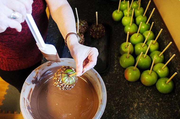 &lt;p&gt;Pat Page drizzles melted chocolate onto an apple already covered in caramel and pecans on Monday afternoon at The Apple Trolley in Evergreen.&lt;/p&gt;