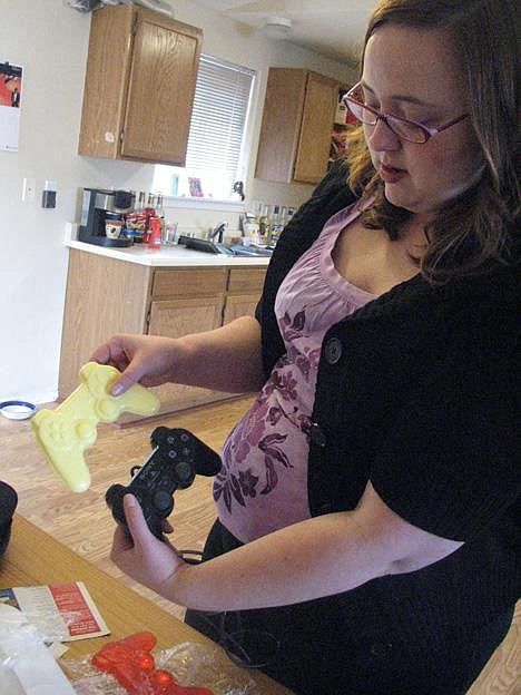 Chrystal Doucette holds one of her homemade soaps up to a real PlayStation 2 video controller in her Moses Lake home. Photo by Lynne Lynch/Columbia Basin Herald