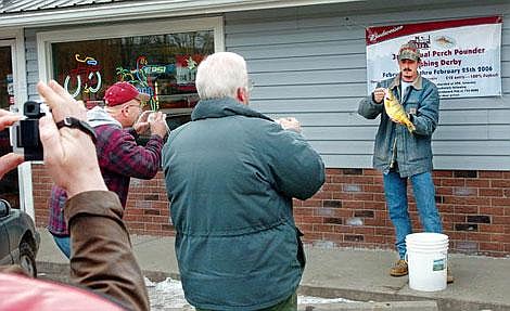 From left, Joe Bloxom, Gary Bowman and Jim Vashro take photos of Josh Emmert and his state-record perch Monday morning at the Scoreboard Pub in Kalispell. Emmert caught the fish Sunday on Stillwater Lake during the Perch Pounder Fishing Derby.&lt;br&gt; Chris Jordan /Daily Inter Lake