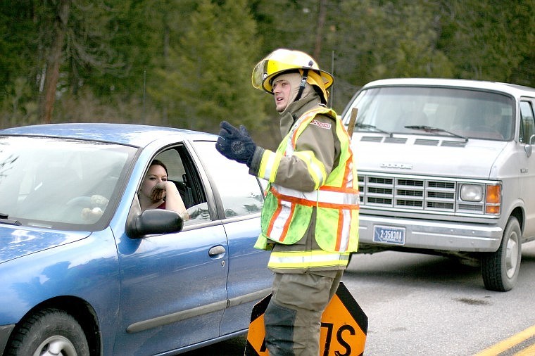 <p>Superior Firefighter Zach Brooks informs a motorist that the road ahead is closed due to fallen trees.</p>