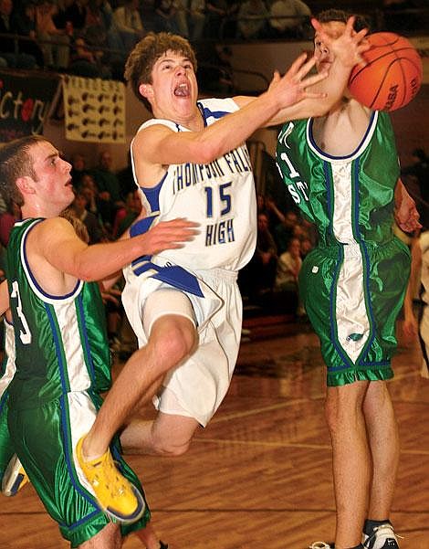 Photo by Ed Moreth Thompson Falls Bluehawk Brian Schenavar drives through the center in an attempt for two points, but is blocked by Valley Christian Eagle defenders at the Western B Divisional Tournament at Polson. The Bluehawks claimed a 72-69 victory over the Eagles Thursday.