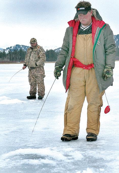 Photos by Adam Herrenbruck Rich Border, foreground, and Luke Di Cola, both of Missoula, stand above their fishing holes waiting for perch to take a bite Saturday on Dog Lake. Though the area has been exposed to warmer weather, Dog Lake still has thick ice.