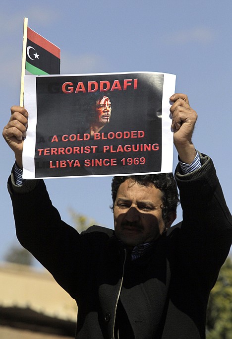 &lt;p&gt;A Libyan anti-government protester, holds a monarchist-era flag, and a poster expressing his accusations, during a demonstration against Libyan leader Moamar Gadhafi, in the southwestern town of Nalut, Libya, Tuesday, March 1, 2011. The town is currently in control of the Libyan anti-government forces.&lt;/p&gt;