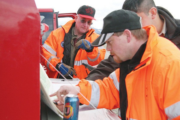 Members of the Lake County Search and Rescue team Bryce Eldridge (foreground) and Ken Caffrey examine a map and plug coordinates into a GPS device to try and locate stranded skiers on Mount. St. Mary's in St. Ignatius. After locating the group, the rescuers verified that they were uninjured and able to safely exit the wilderness.